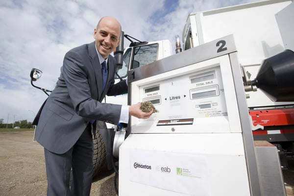 A man in front of a gas pump and a handful of dirt