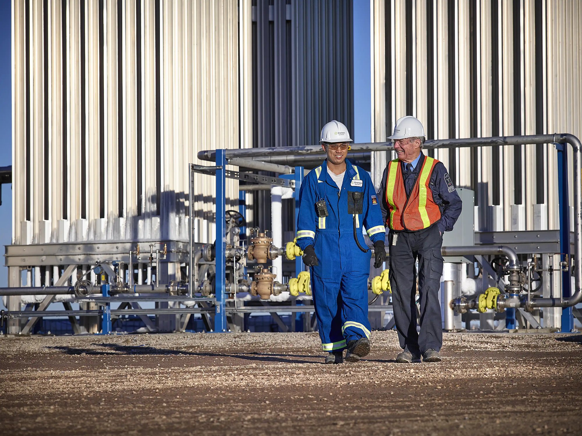 un groupe d'hommes portant des casques et des combinaisons de travail marchant devant une usine