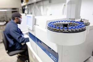 Un homme dans un laboratoire avec de petites fioles dans une machine.