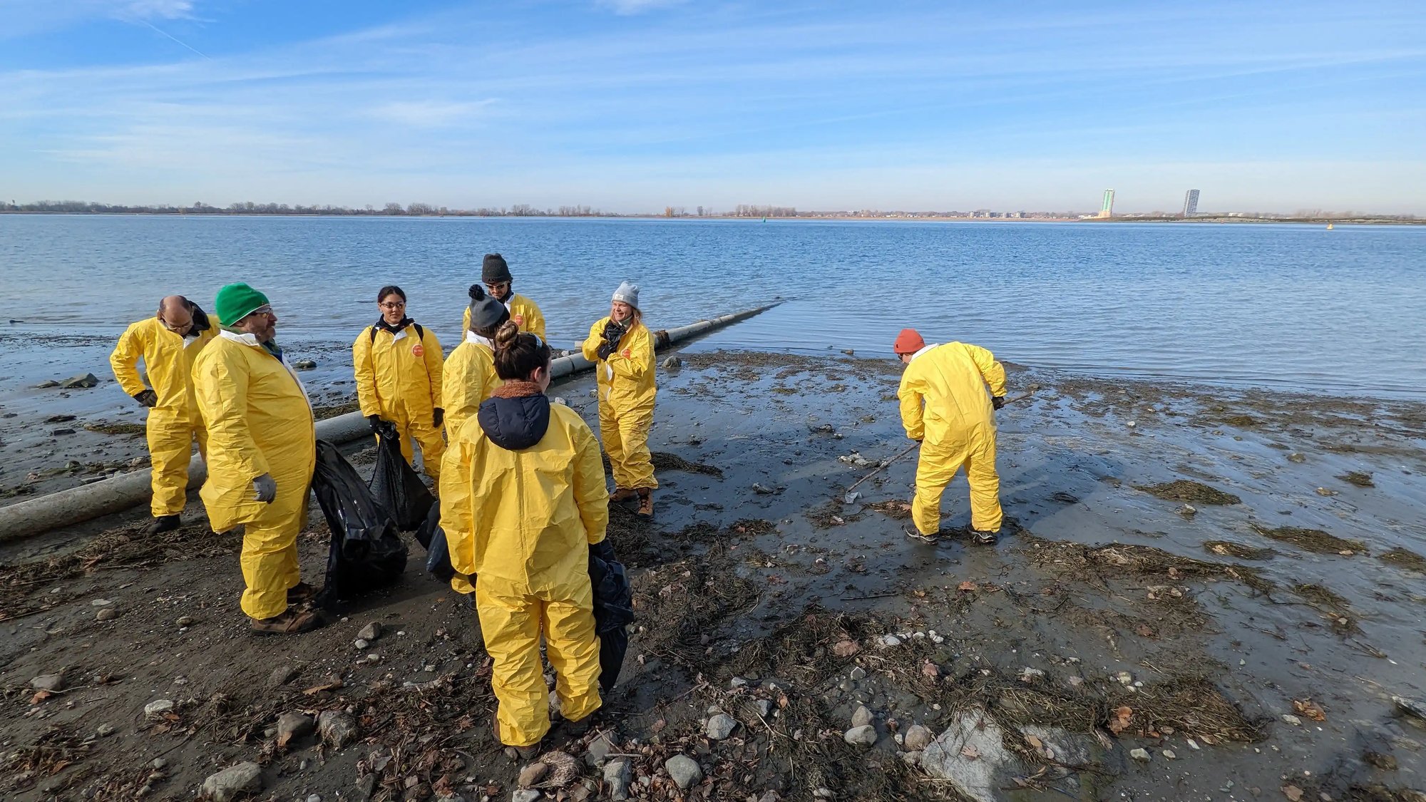 a group of people in yellow suits cleaning a beach