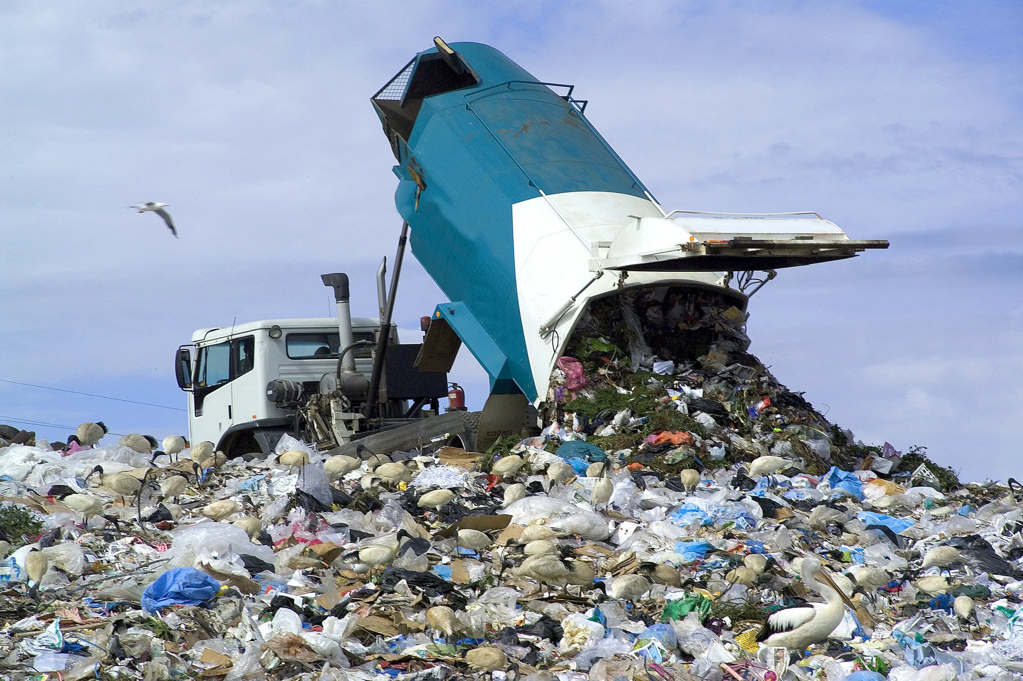 a truck dumping waste into a garbage heap